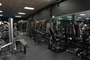 Weight training area at Halo Gym with benches, resistance machines, free weights, and mirrored walls for form checks
